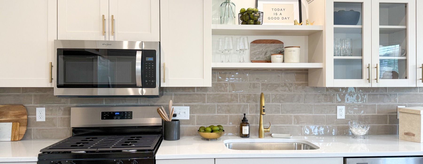 A kitchen with luxury appliances glass front cabinets kitchen island gold accents and hardware dishwasher gas stove and oven microwave extra cabinetry